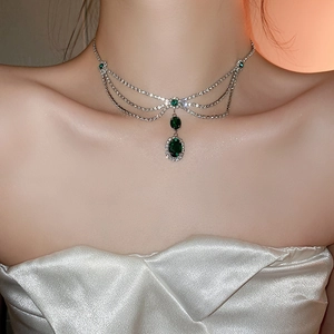 Detail of layered silver necklace with emerald green oval pendant and sparkling zircons