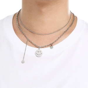 Detail view of double-layered silver smiley pendant necklace with star patterns on model