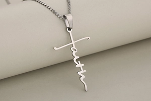 Macro detail of silver stainless steel faith pendant with integrated cross on thin chain