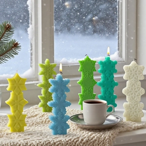 Detailed view of stacked snowflake candles in five pastel colors on a snowy windowsill