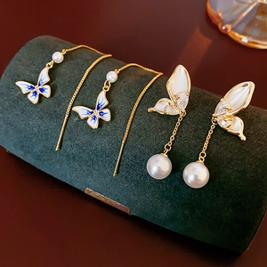 Close-up of 14K gold plated butterfly earrings with pearls on dark green velvet