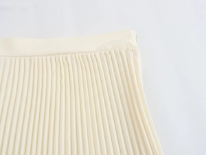 Detail of beige pleated skirt showing fabric texture and hidden side zipper closure