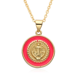 Detailed view of religious Saint Benedict medal pendant with red enamel and gold relief