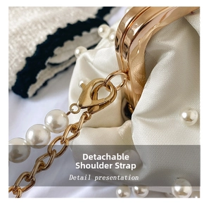 Detail view of the detachable pearl and golden chain strap on a cream satin shell bag