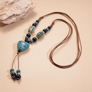 Vue détaillée du pendentif cœur en céramique et perles bleues sur collier tissé main