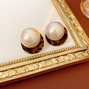 Macro view of leopard print plush earrings with large white round pearls on vintage frame