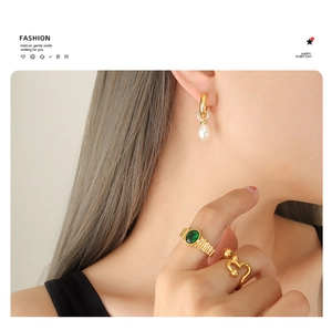 Baroque pearl earrings and gold rings with green gemstone on a model for jewelry style