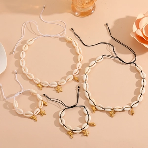 Detail of seashell jewelry set with golden starfish and dolphin charms on cord