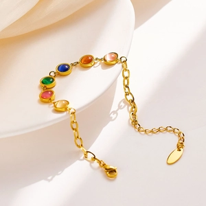 Elegant gold titanium steel bracelet with six colorful cat-eye stones on a white dish