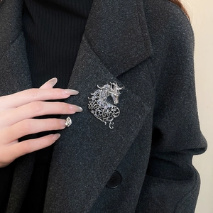 Detail view of a vintage hollowed-out pony brooch with blue and purple crystals on a coat