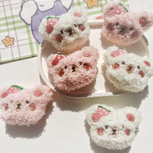 Detailed close-up of plush cartoon bear brooches featuring strawberry embroidery in pink and white