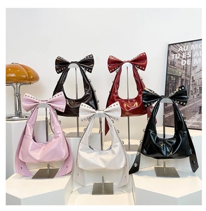Detail of glossy patent leather hobo bags with oversized bows and silver rivet studs
