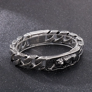Detail of silver tiger relief and Greek key patterns on stainless steel bracelet