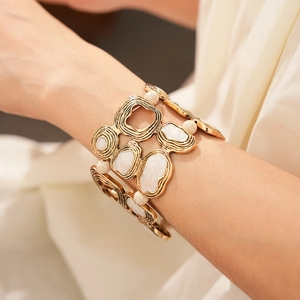 Close-up of vintage golden cuff bracelet with white marble texture and matte finish