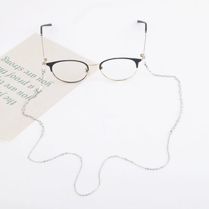 Detail of metal eyewear chain with silver cross on semi-rimless frames over white background