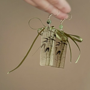 Detail of bamboo pattern earrings with green beads and silk ribbon bows on silver hooks