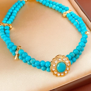 Vue détaillée du collier de perles turquoise vintage avec pendentif fleuri en boîte dorée