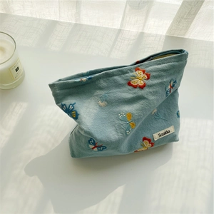 Macro shot of sky blue makeup bag with butterfly embroidery and woven brand label