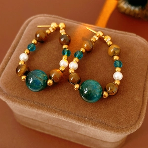 Gros plan de perles œil de tigre, cristal bleu et perle goutte sur créoles vintage