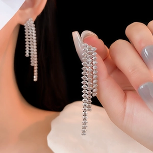 Detailed view of silver tassel earrings with sparkling crystals held by a hand