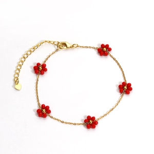 Detail of gold flower bracelet with red beads, lobster clasp and heart charm