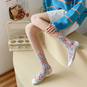 Detail of vintage floral knit socks in cream with blue and red flower embroidery