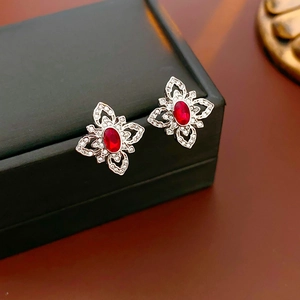 Macro shot of silver flower stud earrings with a red gemstone and micro-pave zircons