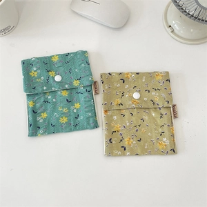 Macro view of blue and yellow floral fabric pouches with secure button closure and label