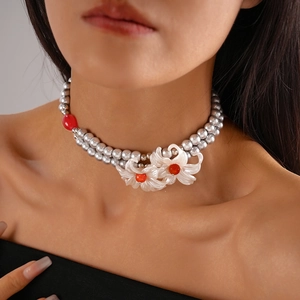 Detail of double-layer grey pearl necklace with white floral accents and red bead center