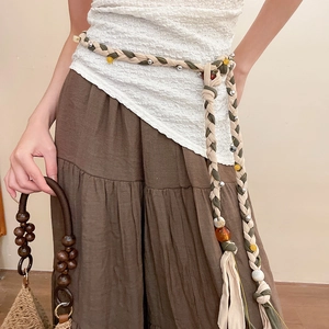 Detail of bohemian hand-woven waist chain with crystal beads and tassels on linen dress