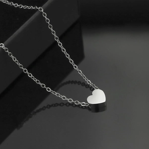 Collier avec pendentif cœur en argent poli sur surface réfléchissante noire et boîte