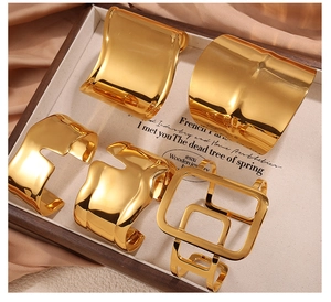 Set of five polished gold geometric bangles featuring irregular wave and hollow square designs