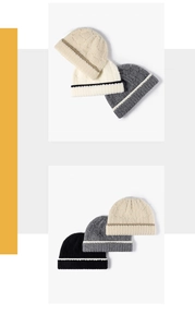Close-up of color-block knit beanies showing thick ribbed texture and striped fold-over cuffs