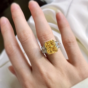 Detailed view of radiant cut yellow gemstone ring with side stones worn on finger