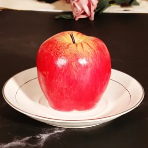 Vela de manzana roja realista con acabado brillante en plato de cerámica blanca decorativa