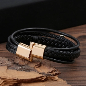 Macro shot of multi-layer black leather bracelet with golden metallic geometric magnetic clasp