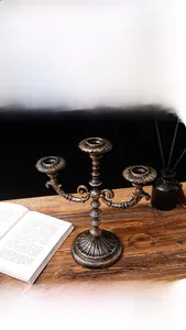 Close-up of vintage bronze 3-arm metal candelabra with embossed base and floral textures