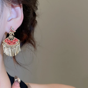 Macro view of Chinese style fan-shaped earrings with red enamel and gold tassels