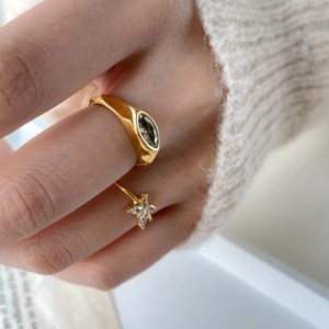 Gold butterfly eye design rings with marquise gemstone on a white knit sweater background