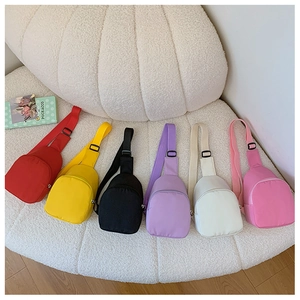 Mini nylon chest bags for kids shown in six bright colors on a textured white chair