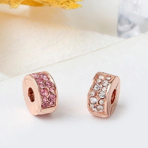 Gros plan de charms DIY en or rose sertis de cristaux pavés roses et blancs