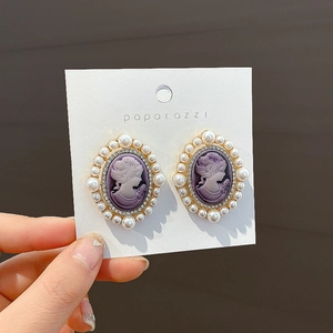 Gros plan de boucles d'oreilles camée vintage avec base violette et bordure en perles