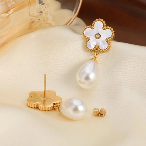 Detail of flower-shaped earrings with mother of pearl petals and teardrop pearls