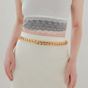 Close-up of a chunky gold acrylic link belt styled with a white lace and knit dress