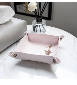 Close-up of pink faux leather storage tray with four-corner snaps on marble tabletop
