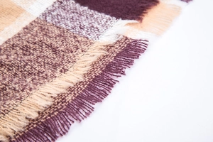 Close-up of soft plaid fabric texture with fringes in purple, beige and brown