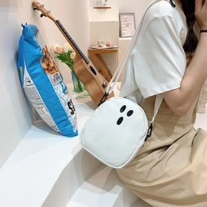 Détail du sac bandoulière fantôme blanc avec sangle en nylon porté dans un décor d'intérieur
