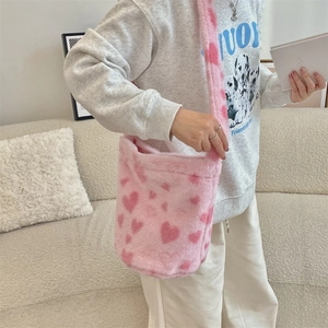 Detailed shot of pink plush shoulder bag with heart patterns on a cozy sofa setting