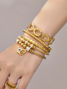 Détail de bracelets plaqués or avec pendentif cœur, gravure Love et ornements en zircone