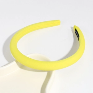 Detailed view of a bright yellow fabric headband with a black HANDMADE woven label